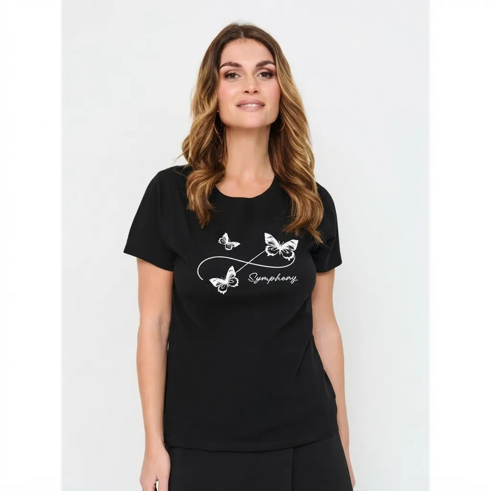 A woman modeling a black short-sleeve t-shirt with a white graphic print of butterflies and the word 'Symphony' on the front, set against a plain light gray background.