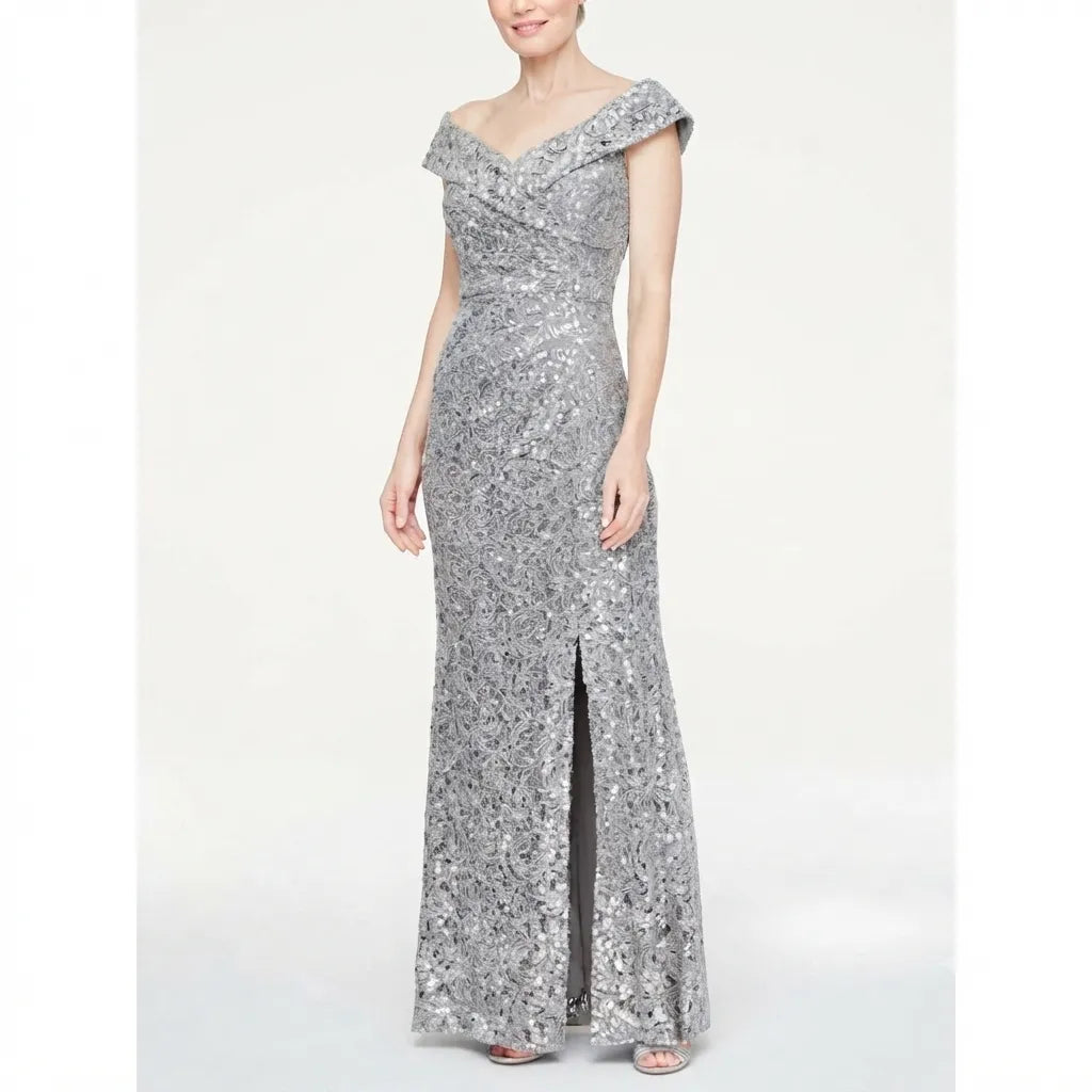 A woman modeling a floor-length silver sequined gown with an off-the-shoulder neckline, fitted silhouette, and front slit, photographed against a plain light gray studio background.