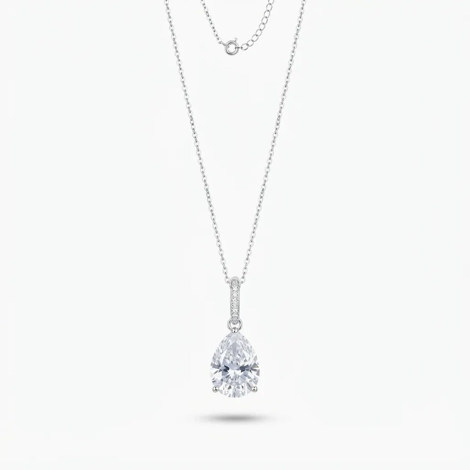 A silver-toned pendant necklace featuring a pear-cut clear gemstone in a prong setting, with a delicate chain and a second layered chain detail at the top, shown on a light gray background.