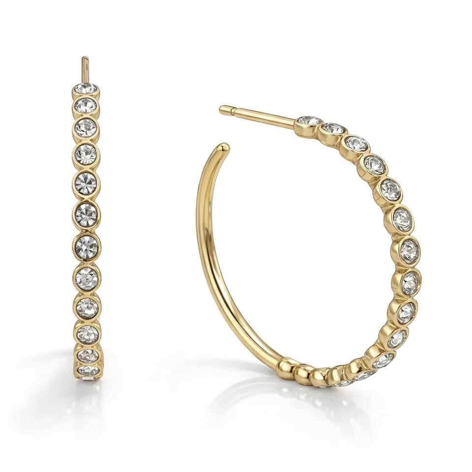 A pair of gold hoop earrings adorned with clear round-cut rhinestones set along the outer edge, shown on a clean white background.