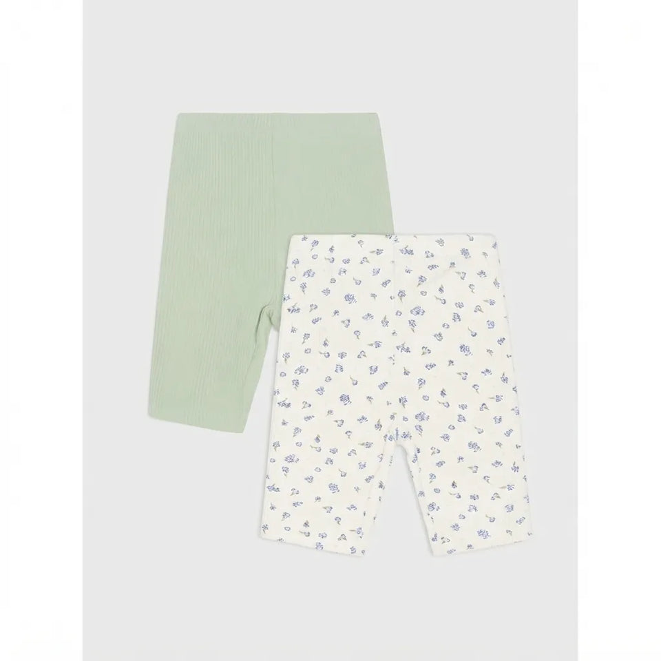 Two pairs of baby leggings laid flat on a light gray background. The pair on the left is solid pale mint green, and the pair on the right is white with a small scattered blue floral print.