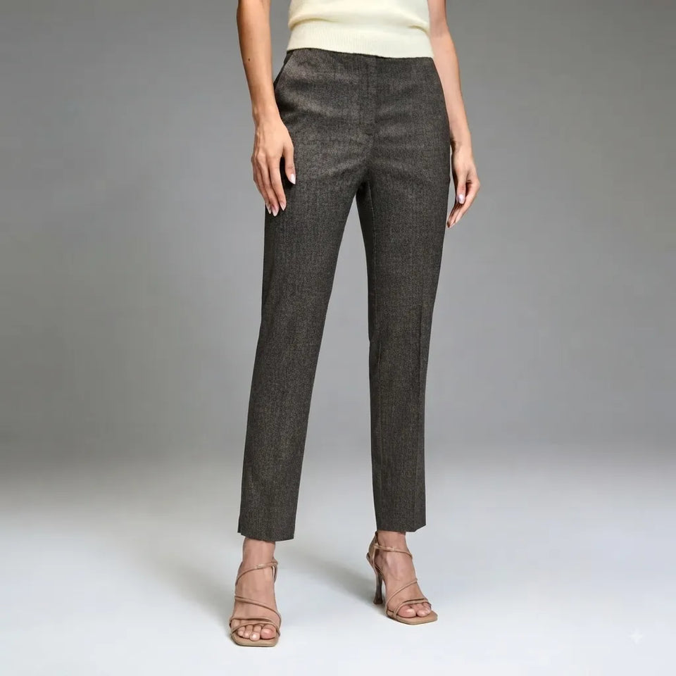 A model wearing a pair of dark gray textured straight-leg trousers, paired with a cream top and beige strappy heels, against a neutral gray studio background.