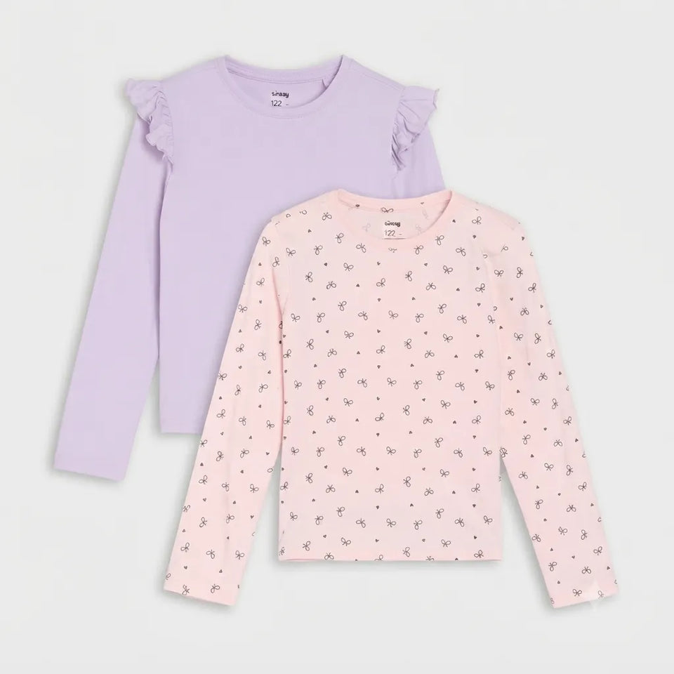 Two girls' long-sleeve tops layered together on a light gray background. The top in back is light lavender with ruffled shoulders, and the top in front is light pink with a small scattered floral print.