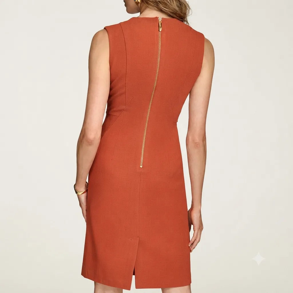 A woman wearing a sleeveless rust-orange dress, shown from the back against a light gray studio background. The dress features a structured silhouette with a prominent gold zipper running down the center back.