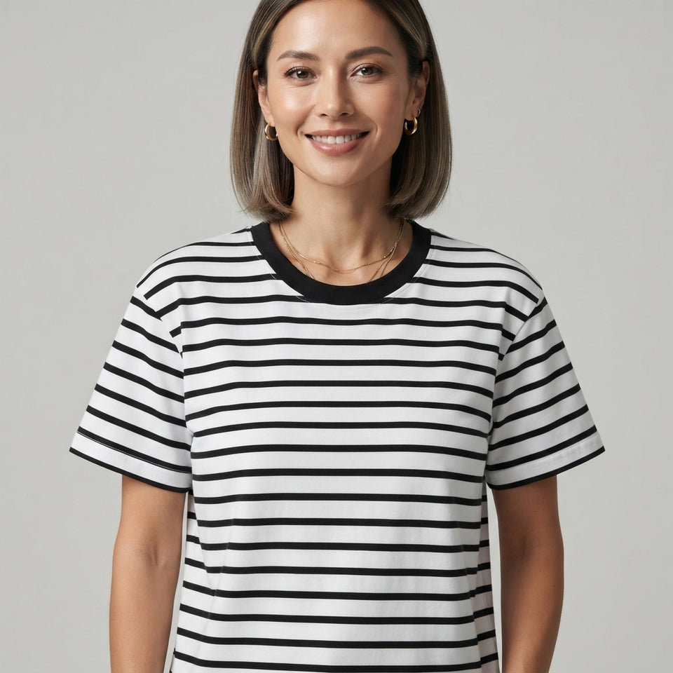 A woman wearing a black and white horizontally striped short-sleeve t-shirt with a solid black crew neck, photographed against a neutral light gray background.