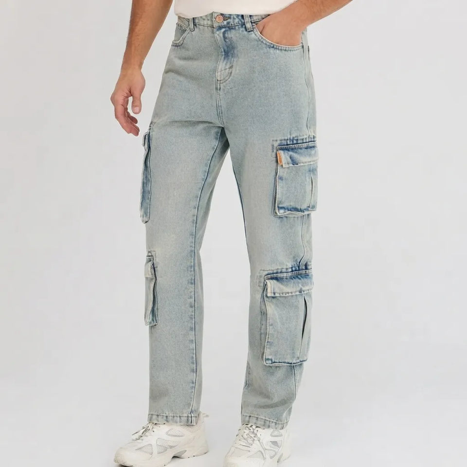 A person wearing light-wash blue denim cargo jeans with large flap pockets, shown from the waist down against a plain light gray studio background.