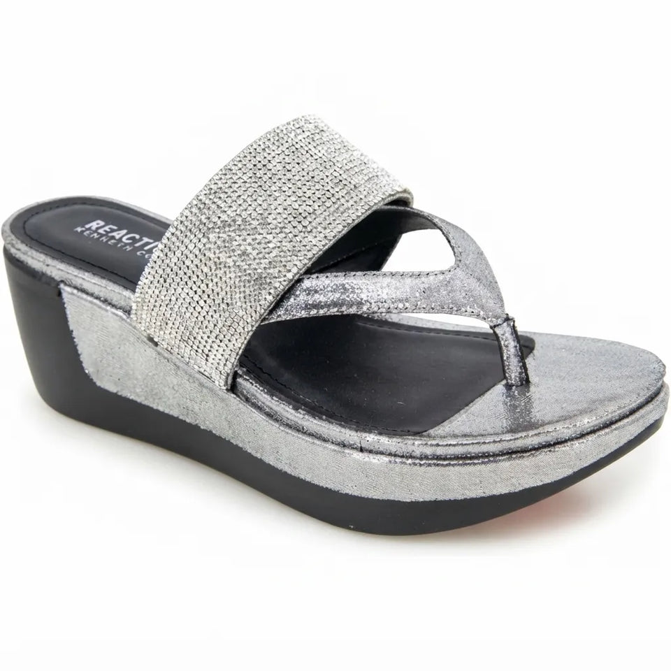 A single women's wedge sandal with a glittery silver thong strap and a wide textured silver band, set on a black wedge sole against a white background.