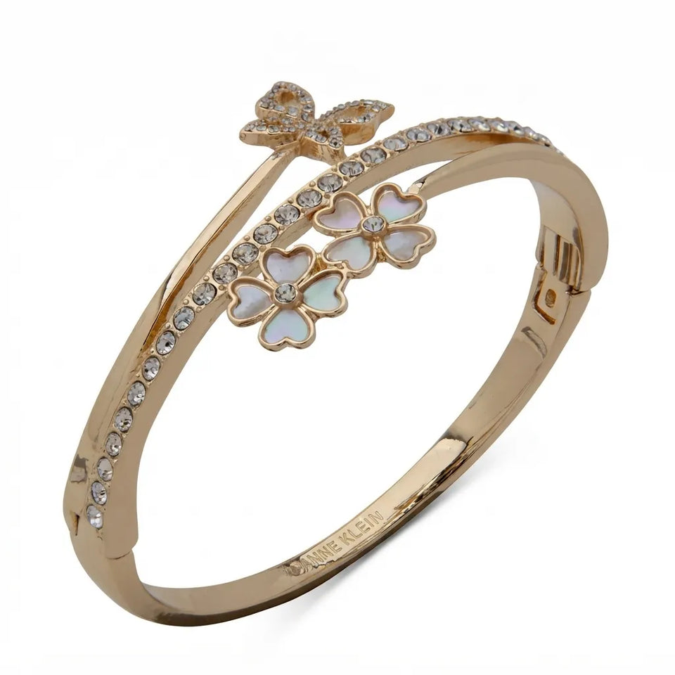 A gold-plated bangle bracelet featuring a butterfly and flower motif with iridescent white inlay, accented by clear rhinestones, shown on a white background.