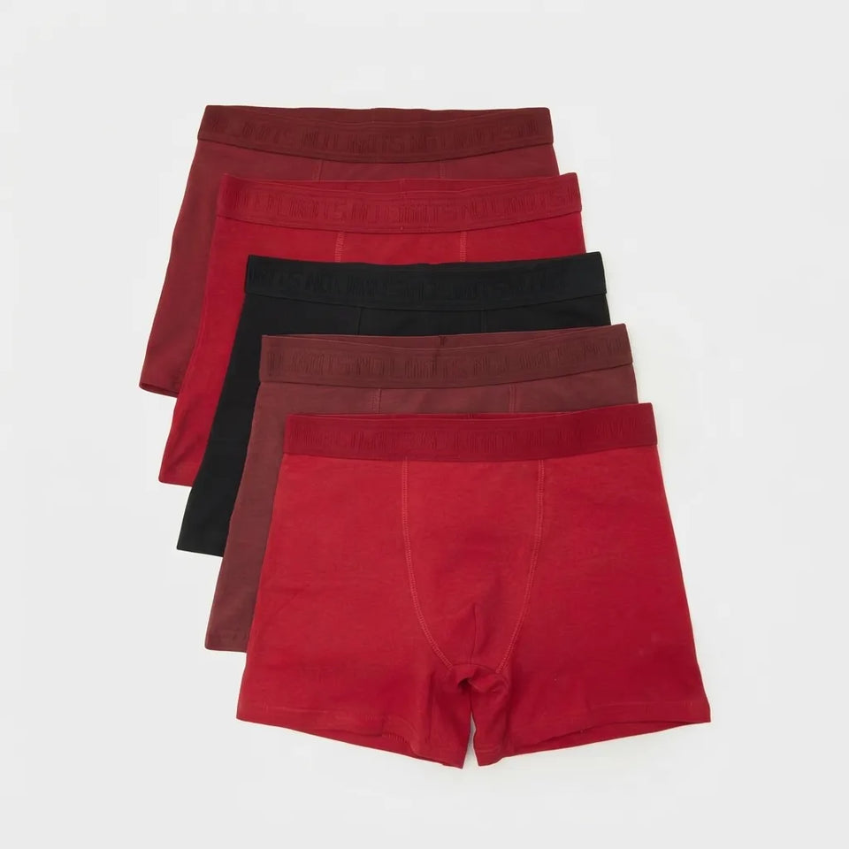 A set of five men's boxer briefs in various shades of red, burgundy, and black, arranged in a neat diagonal stack on a light gray background.