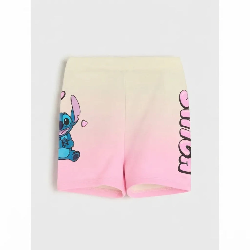A pair of women's athletic shorts featuring a cream-to-pink gradient, with a cartoon character graphic on the left leg and vertical text on the right leg, shown against a light gray background.