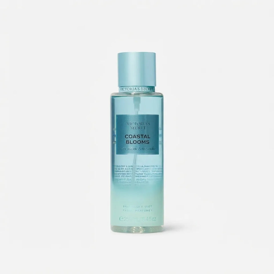 Victoria's Secret Coastal Blooms Hair Oil in a clear bottle showing a light blue gradient liquid, with a matching light blue cap, on a light gray background.