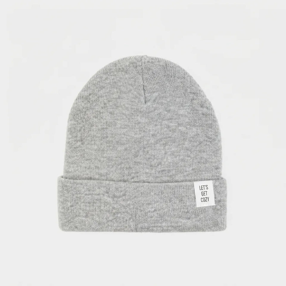 A light gray heather knit beanie hat with a folded cuff, featuring a small white rectangular tag on the side that reads 'LET'S GET COZY'. The hat is photographed against a clean, solid white background.
