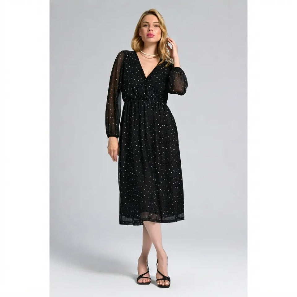A woman modeling a black midi dress with a delicate white polka dot pattern, sheer long balloon sleeves, and a V-neckline, photographed against a neutral gray studio background.