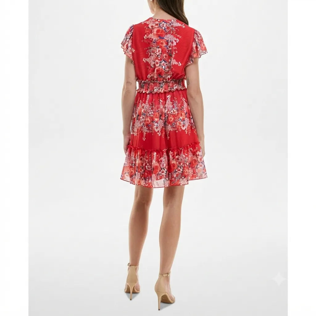 A woman modeling a red tiered mini dress with a white and pink floral pattern, shown from the back against a plain white studio background.