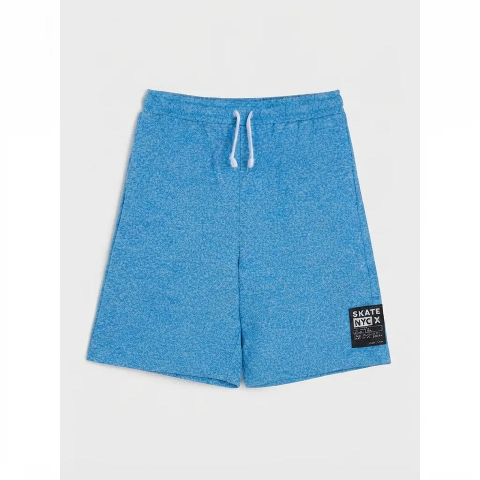 Blue heathered athletic shorts with a white drawstring and a black 'Skate NY X' brand patch on the lower left hem, displayed flat against a light gray background.