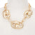 A chunky gold chain necklace with oversized interlocking links, displayed on a white mannequin bust.