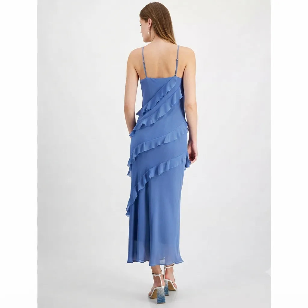 A woman wearing a blue ruffled spaghetti-strap maxi dress, shown from the back against a light gray studio background.