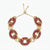 A gold chain link choker necklace embellished with rows of deep red rhinestones, displayed on a clean white background.