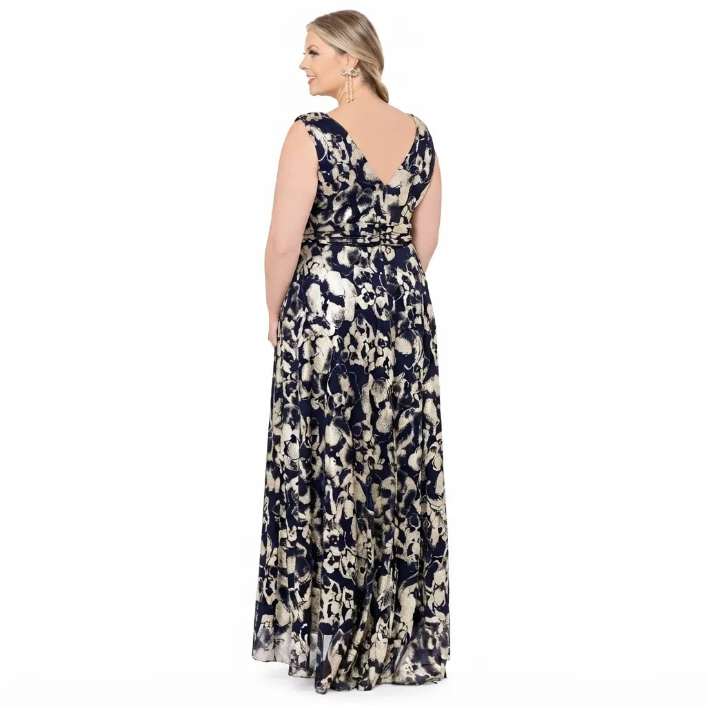 A woman modeling a sleeveless, floor-length maxi dress from the back, featuring a navy blue and beige abstract floral pattern, on a solid white background.