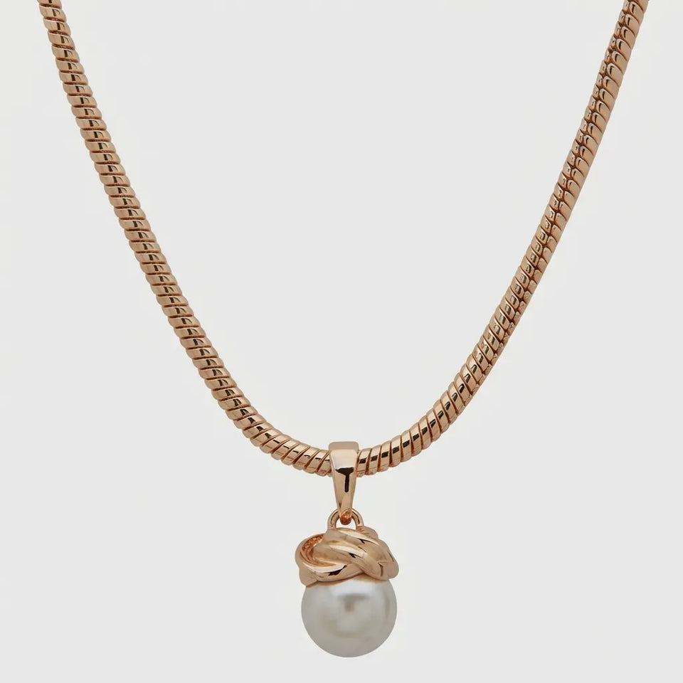 A rose gold snake chain necklace featuring a pendant with a twisted knot design and a single white pearl drop, shown against a light gray background.