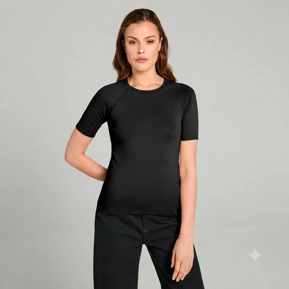 A woman modeling a black short-sleeve crewneck athletic top with raglan sleeves, paired with black pants, against a solid light gray studio background.