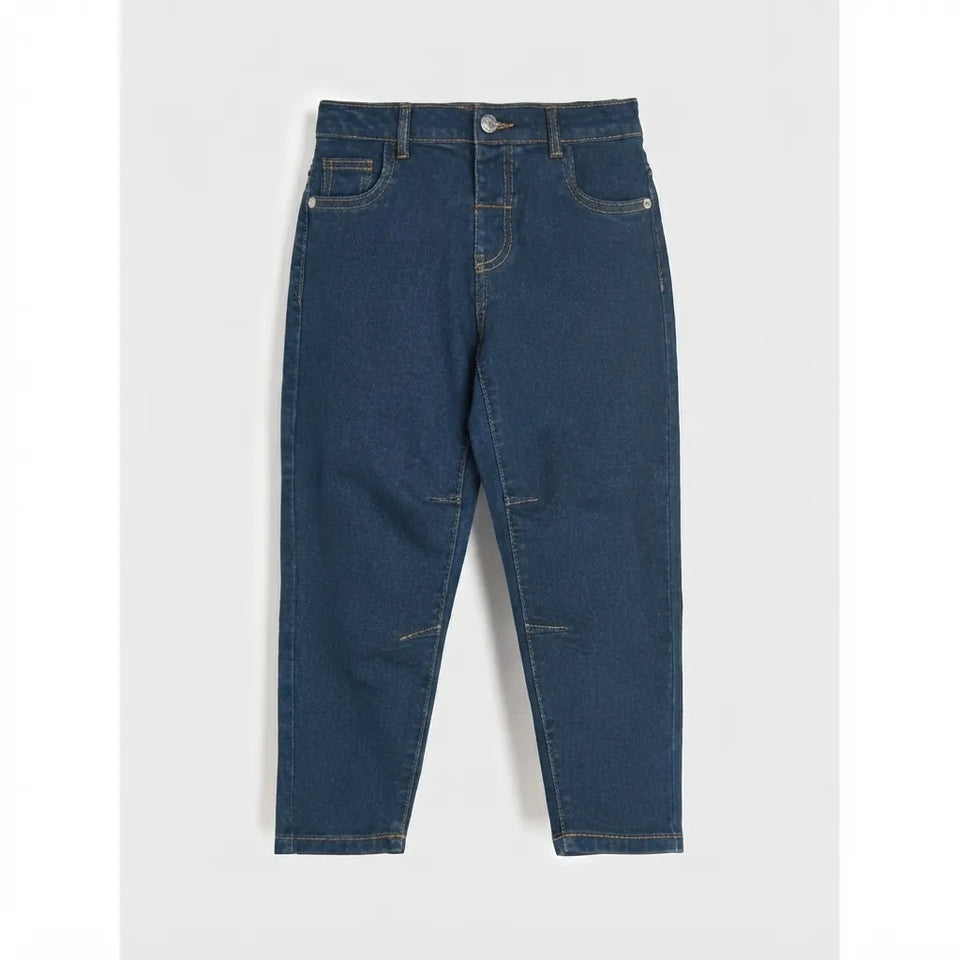 A pair of dark blue denim jeans with a tapered, cropped leg and distressed details on the front and knees, shown flat against a light gray background.
