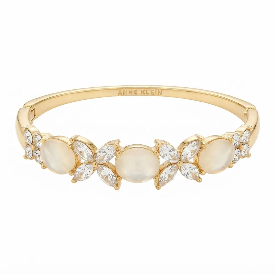 Gold band ring with five floral clusters featuring round milky white cabochons and marquise-cut clear stones, with 'ANNE KLEIN' engraved inside the band.