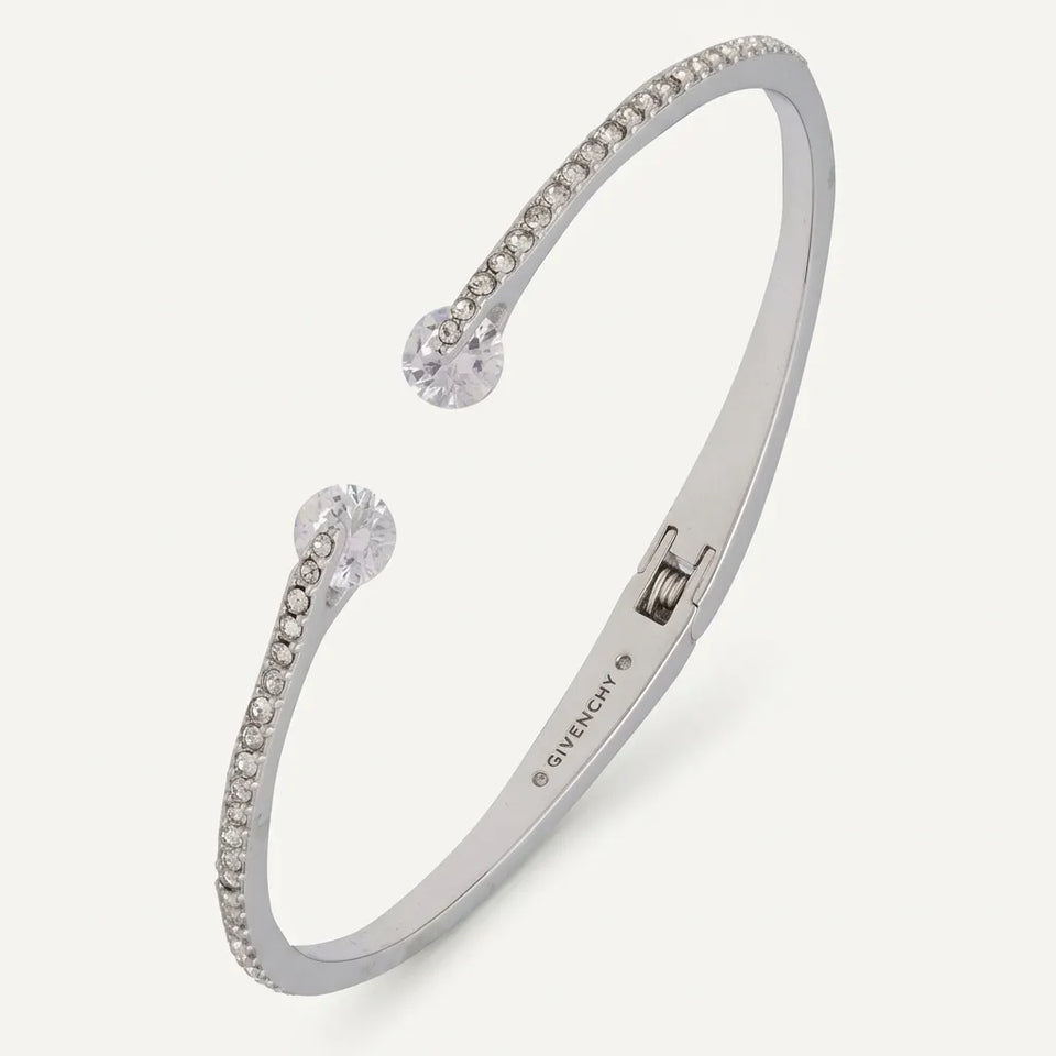 A Givenchy silver-toned cuff bracelet with clear crystal accents, shown on a light beige background.