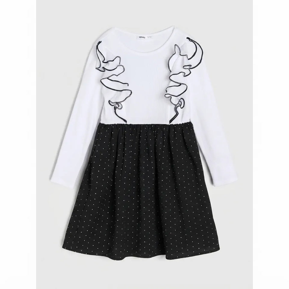 A girls' long-sleeve dress with a white upper bodice featuring black outline applique details, and a black flared skirt with small white polka dots, shown against a light gray background.