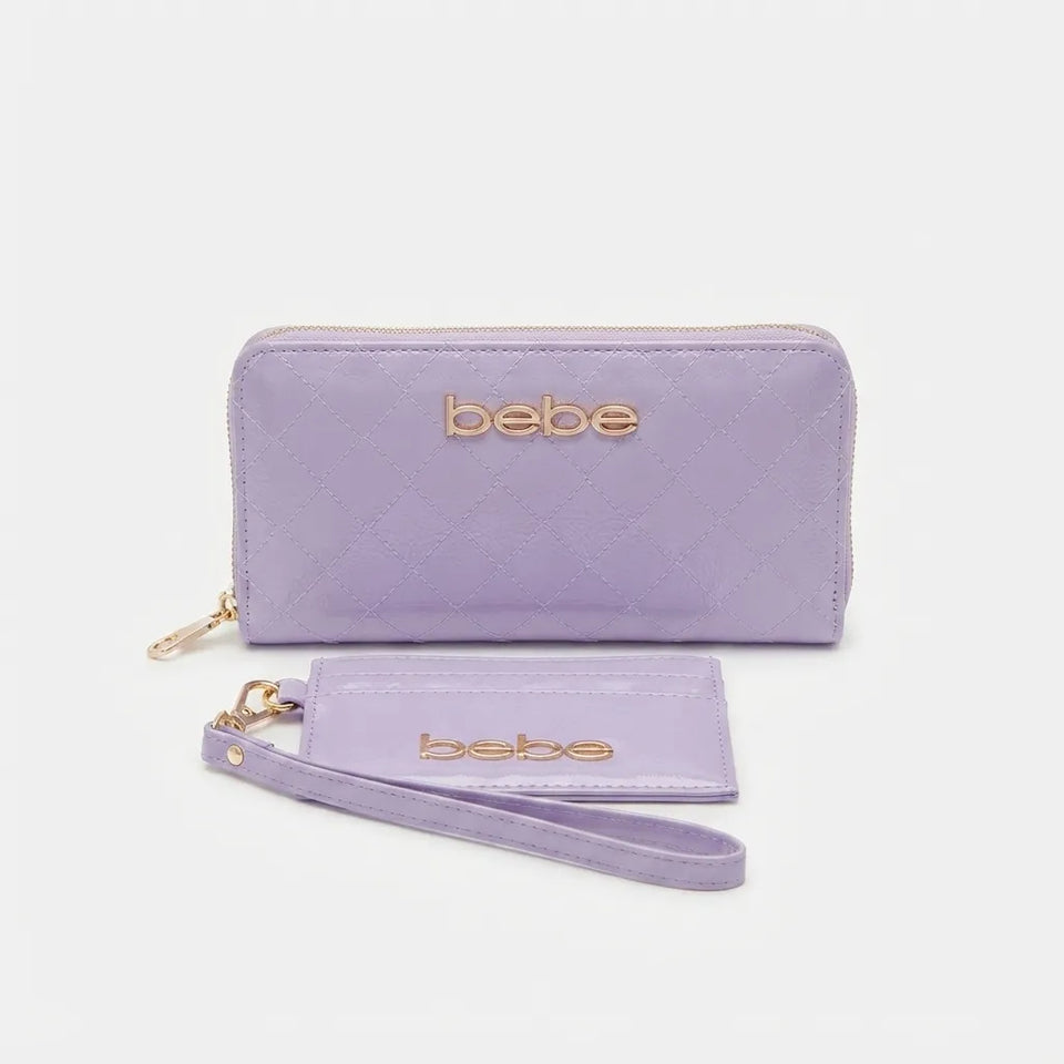 A light purple zip-around wallet with a matching wristlet strap and card holder, both featuring the brand name 'bebe' in gold lettering, set against a plain light gray background.