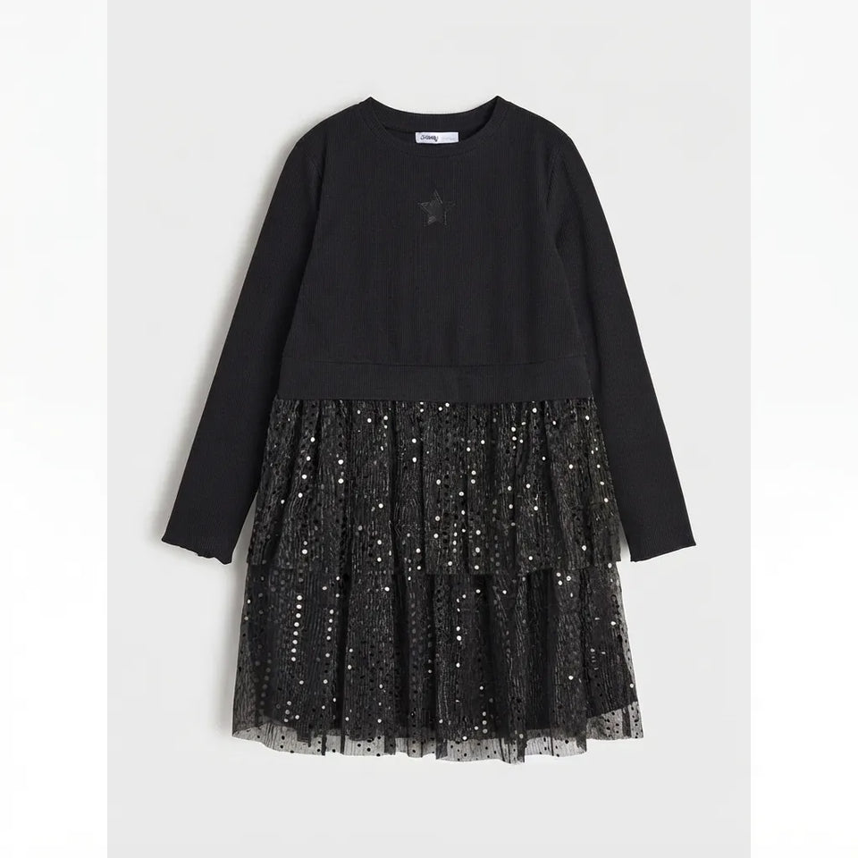 A black long-sleeve dress with a solid black top and a tiered tulle skirt covered in small silver sequins, shown against a light gray background.