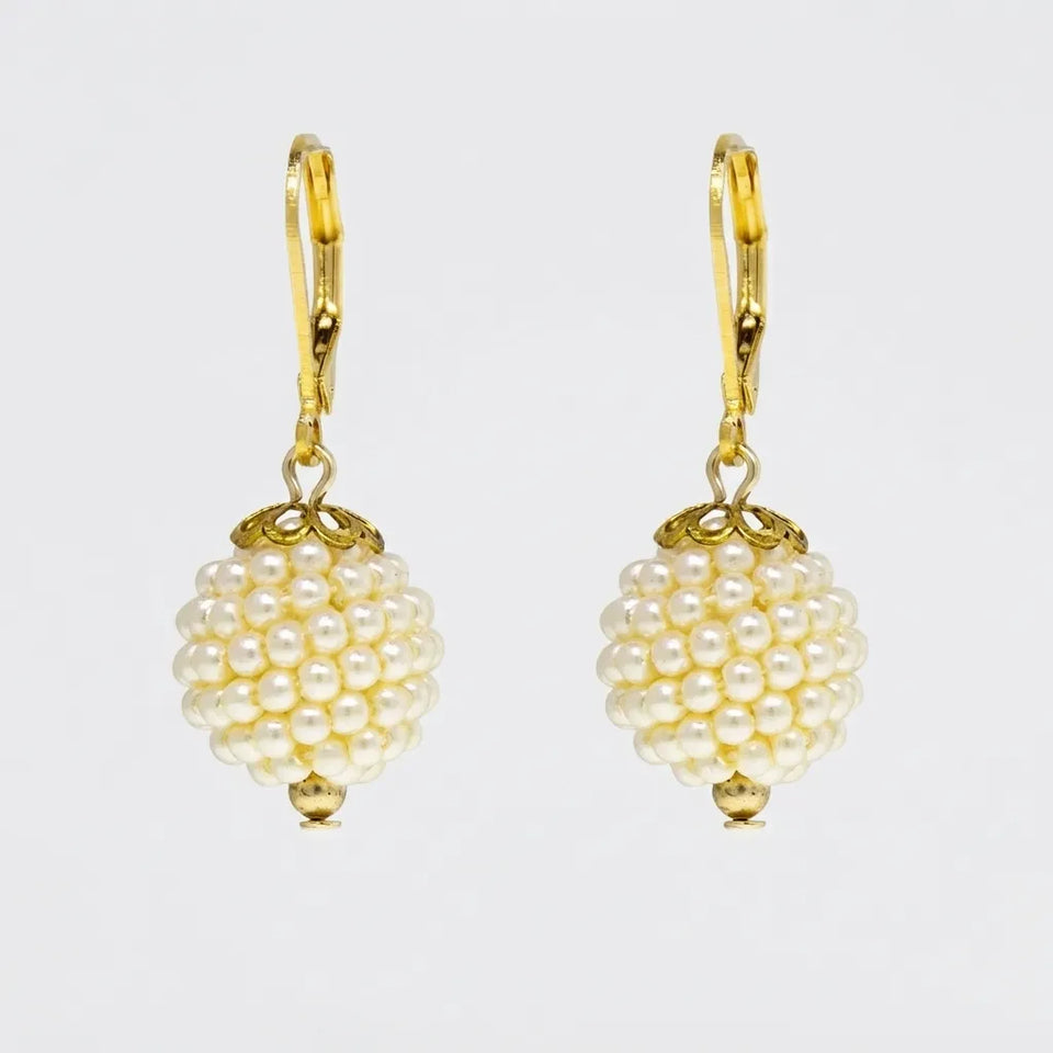 A pair of gold leverback drop earrings featuring a cluster of small white faux pearls shaped like a berry, suspended from gold hooks on a light gray background.
