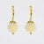 A pair of gold leverback drop earrings featuring a cluster of small white faux pearls shaped like a berry, suspended from gold hooks on a light gray background.