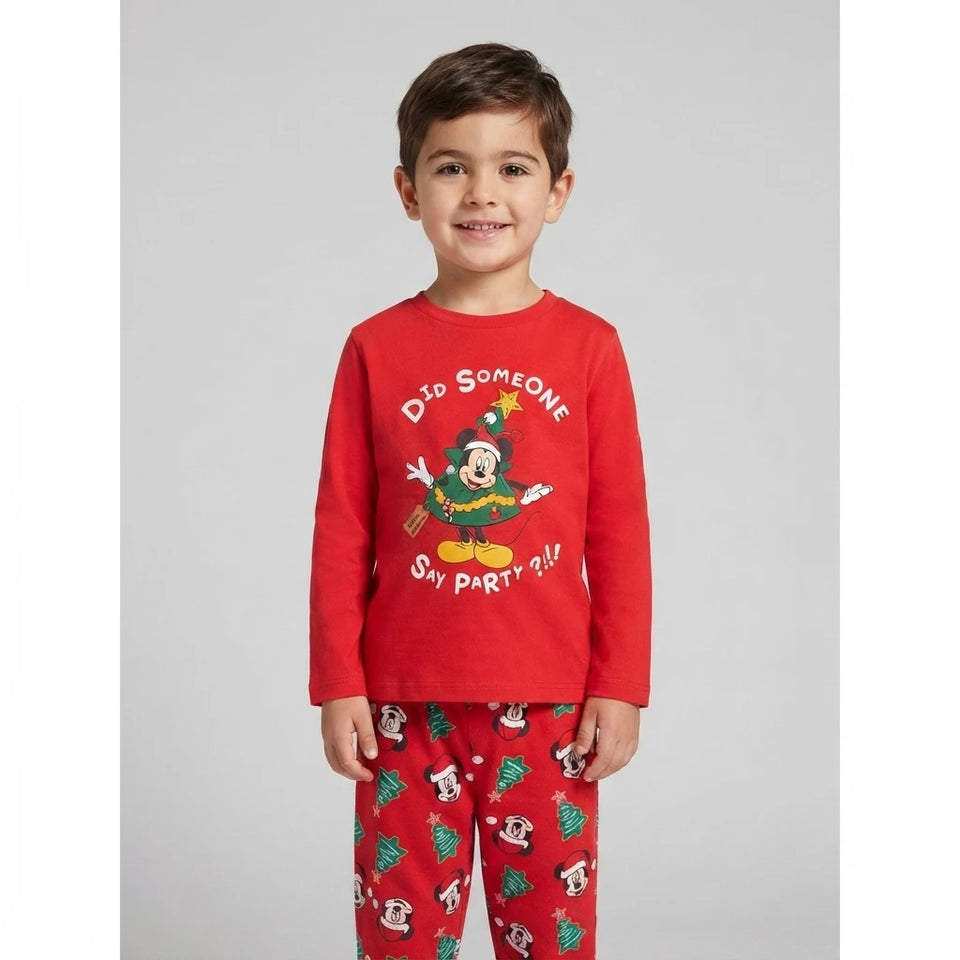 A young boy wearing a red long-sleeve pajama top with a Mickey Mouse Christmas graphic and the text 'Did Someone Snip Party?!!' and matching red pajama pants with a Christmas tree and character print, photographed against a light gray studio background.