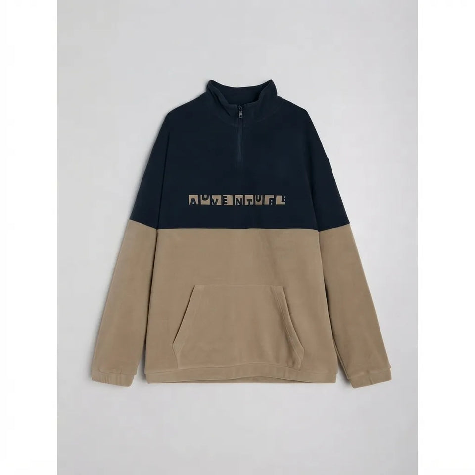 A colorblock quarter-zip pullover sweatshirt with a navy blue upper section, beige lower body and sleeves, and a beige graphic text print across the chest, displayed flat against a light gray background.