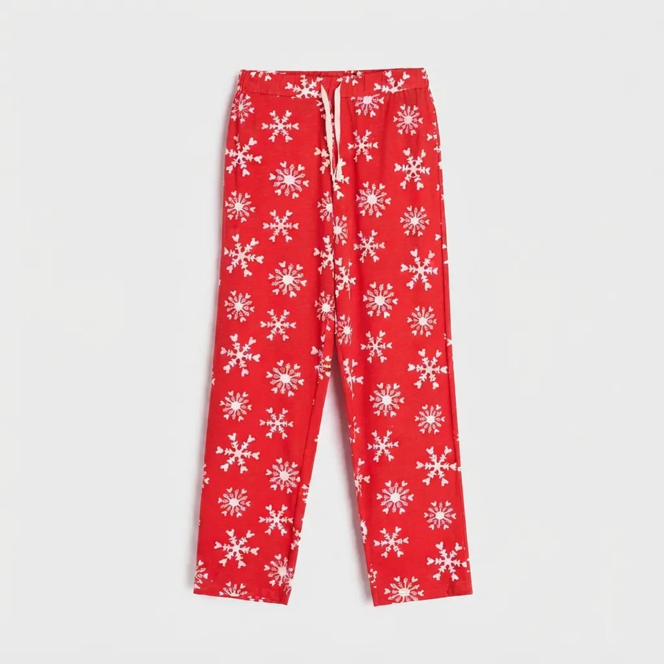 Red lounge pants with an all-over white snowflake pattern and a white drawstring waist, shown flat against a light gray background.