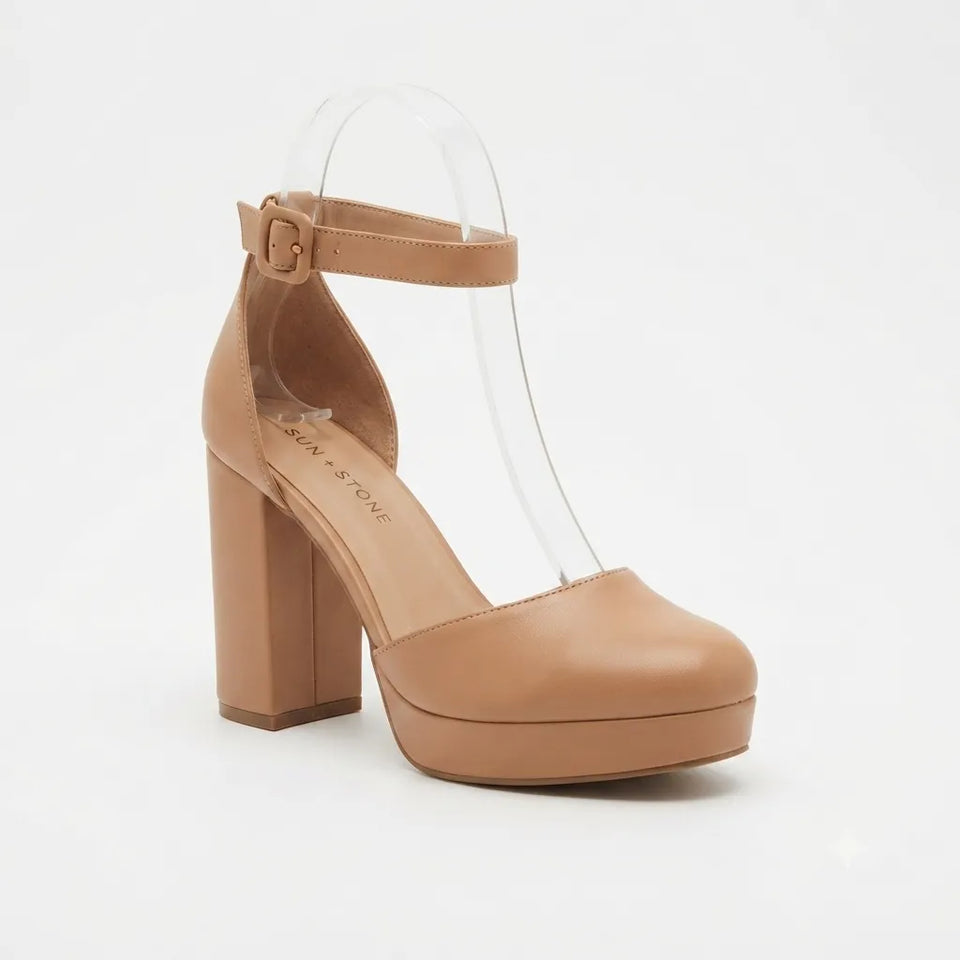 A tan platform high-heeled sandal with an ankle strap and clear plastic T-strap details, shown against a plain white background.