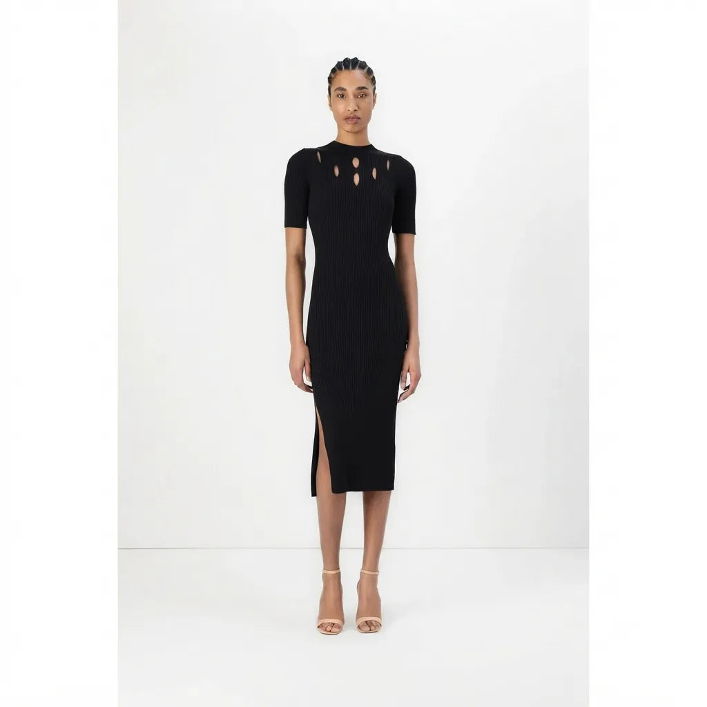 A model wearing a black short-sleeve ribbed midi dress with cutout details at the neckline and a thigh-high slit, paired with beige high-heeled sandals, set against a plain white studio background.