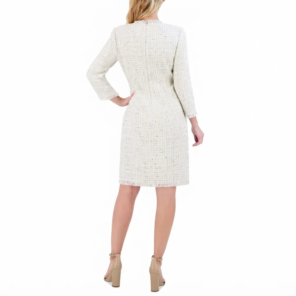 A woman viewed from the back wearing a knee-length cream tweed dress with three-quarter sleeves and beige high-heeled sandals against a plain white background.