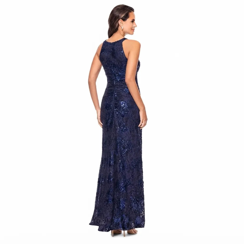 A woman modeling a sleeveless, high-neck floor-length gown with a fitted waist and flared skirt, covered in dark blue sequins and lace, shown from the back against a plain white background.