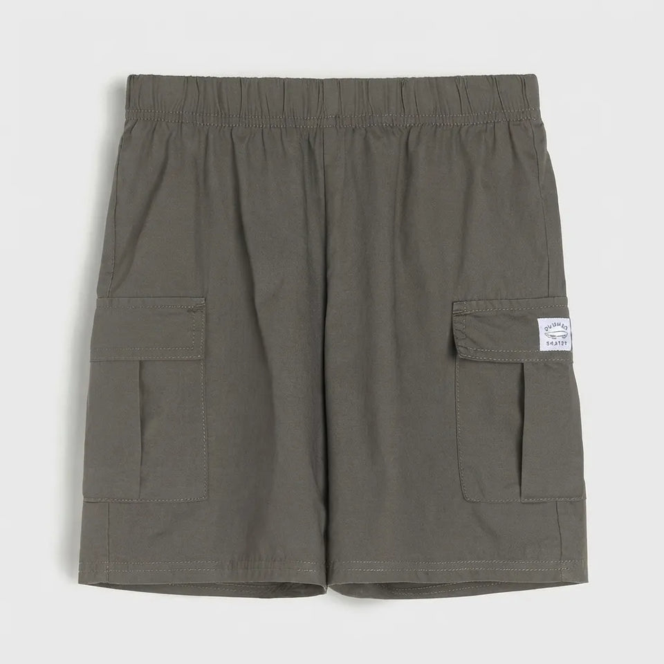 A pair of olive green cargo shorts with an elastic waistband, featuring two large side cargo pockets and a small white brand label on the right pocket, shown against a light gray background.