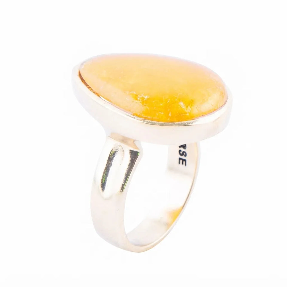 A silver ring featuring a large, smooth, oval-shaped yellow stone, likely amber or a polished gemstone, set against a plain white background.