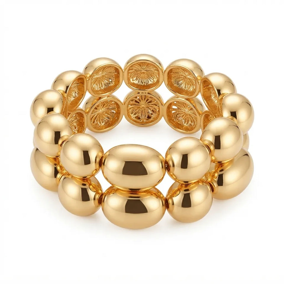 A gold-toned beaded stretch bracelet featuring alternating smooth oval beads and round beads with embossed floral details, shown on a clean white background.