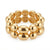 A gold-toned beaded stretch bracelet featuring alternating smooth oval beads and round beads with embossed floral details, shown on a clean white background.