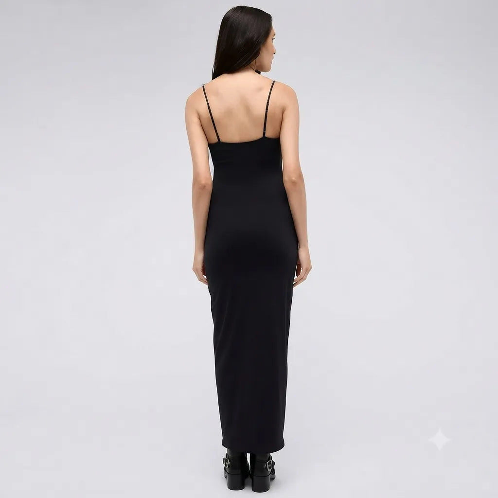 A woman viewed from the back wearing a black spaghetti-strap maxi dress and black platform heels against a light gray studio background.