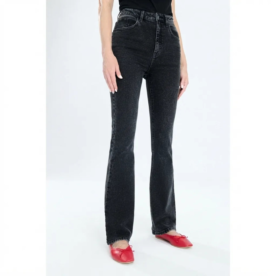 A model wearing a pair of high-waisted, dark gray/black flare jeans with red pointed flats, shown from the waist down against a white studio background.