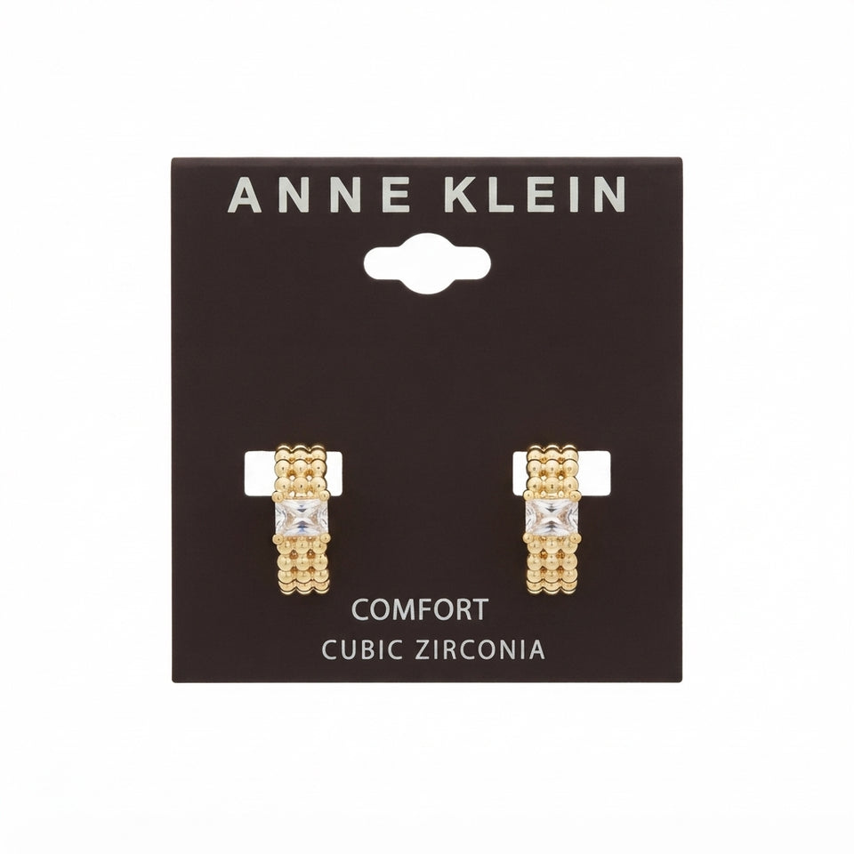 A pair of gold-tone Anne Klein Comfort Cubic Zirconia earrings mounted on a dark brown display card against a white background.