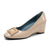 A single women's patent leather wedge pump in a light beige/champagne color, featuring a square metallic buckle detail on the toe and a dark teal-blue interior lining, shown against a plain white background.