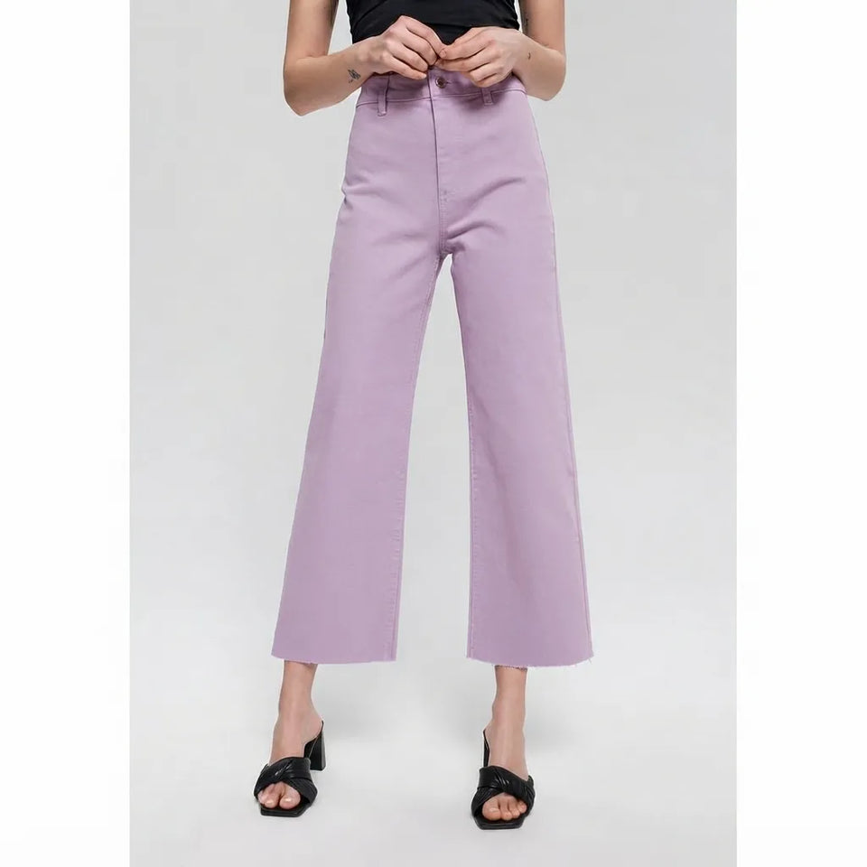 A model wearing lavender wide-leg cropped pants with a black top and black heeled sandals, shown from the waist down against a light gray studio background.