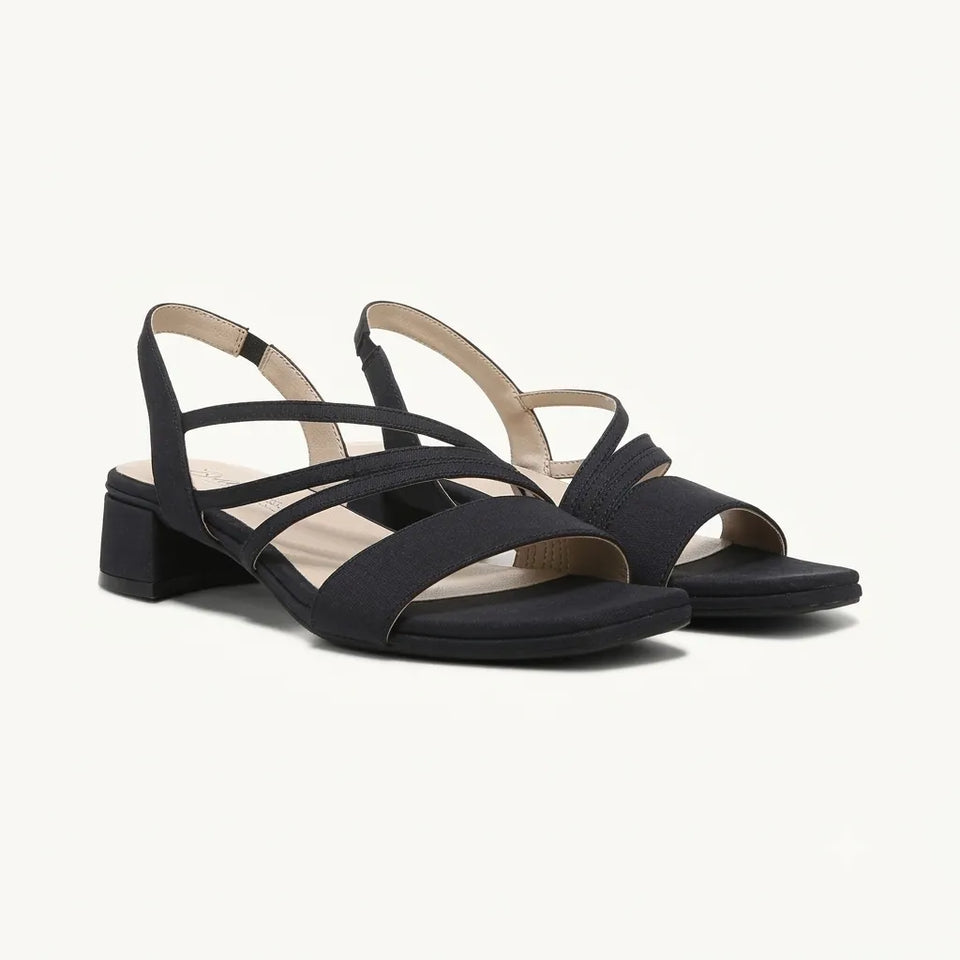 A pair of women's black strappy slingback sandals with a low block heel, shown from a three-quarters angle on a light cream background.
